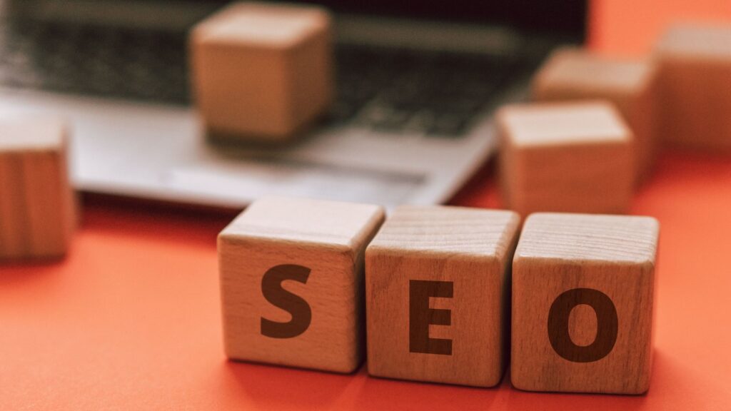 Wooden blocks spelling SEO on a laptop keyboard, symbolizing the connection between web design and SEO.
