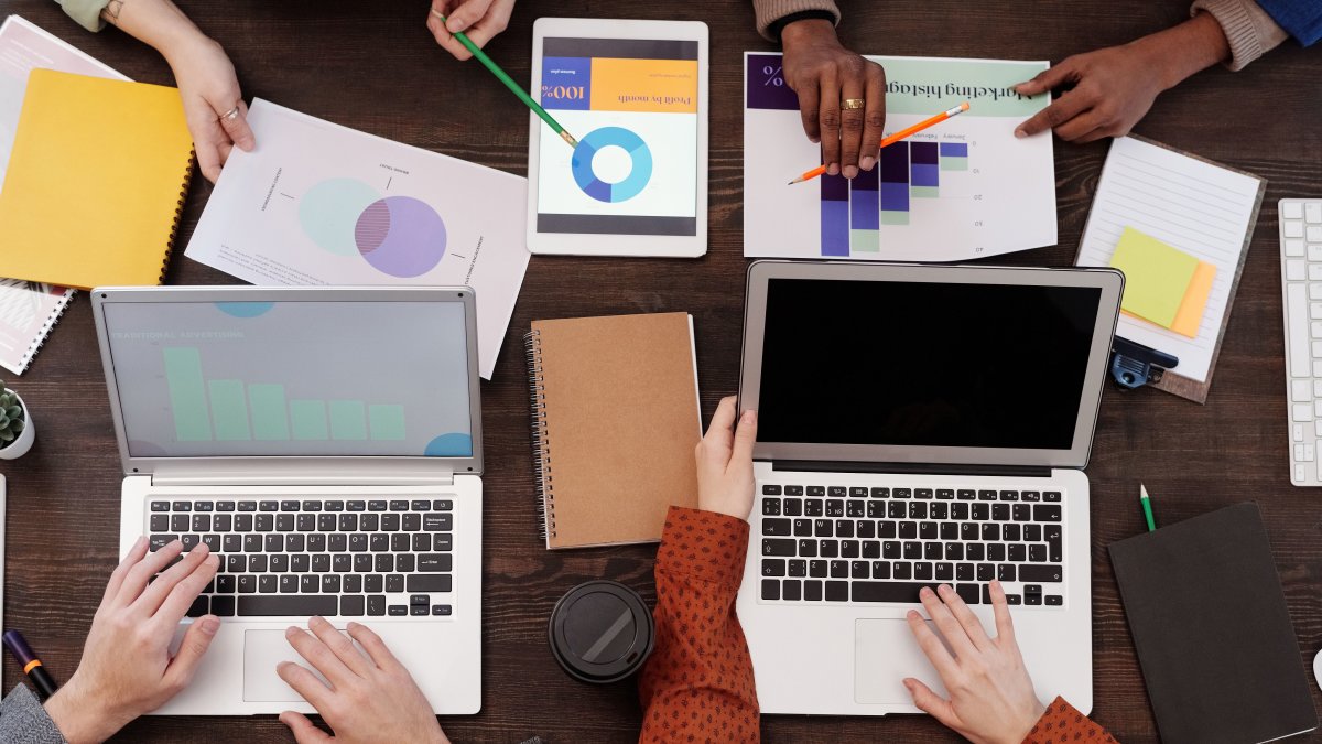 Overhead view of a team discussing digital marketing strategies with laptops and charts