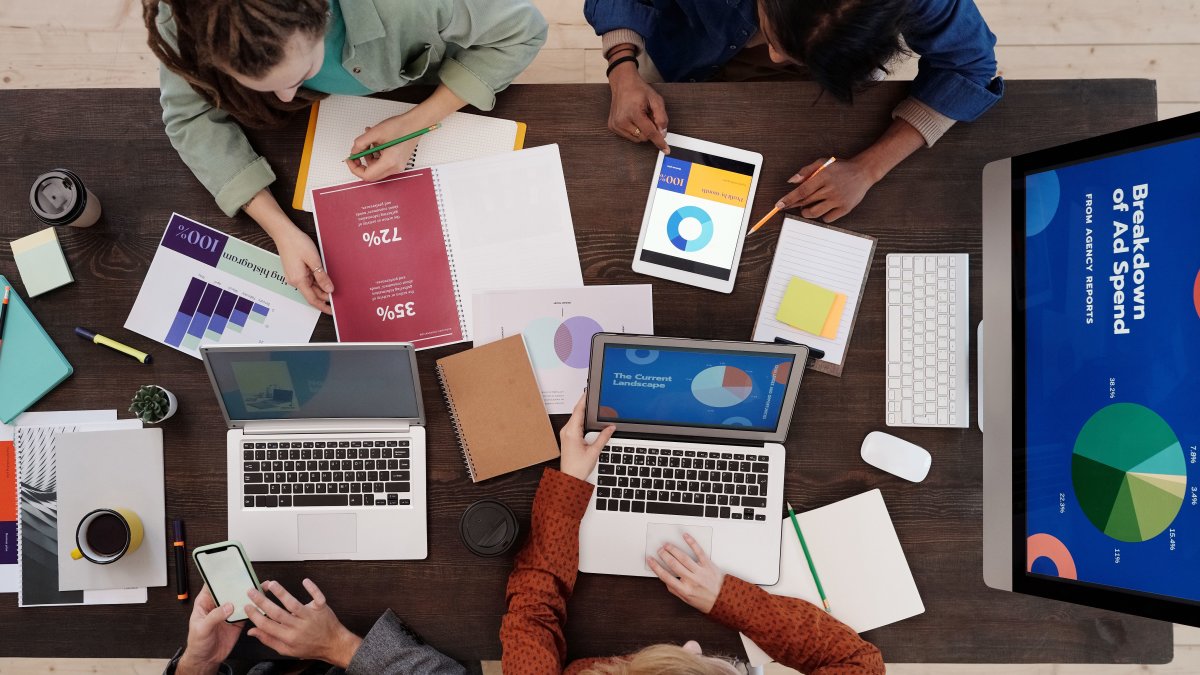 A diverse team collaborating on digital marketing strategies at a desk, using laptops and tablets